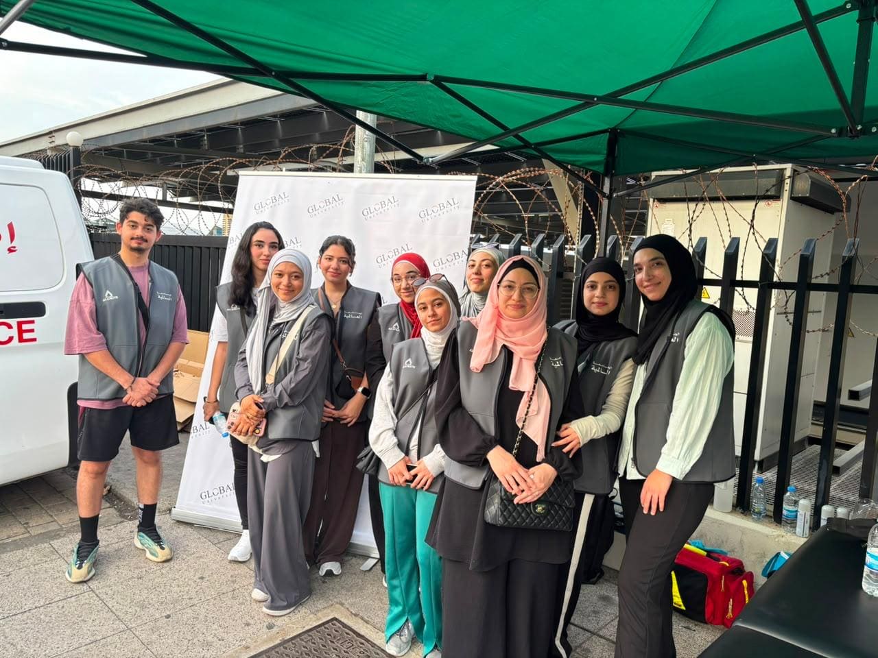 أعضاء الفريق الصحي في الجامعة العالمية أمام خيمة الدعم الطبي