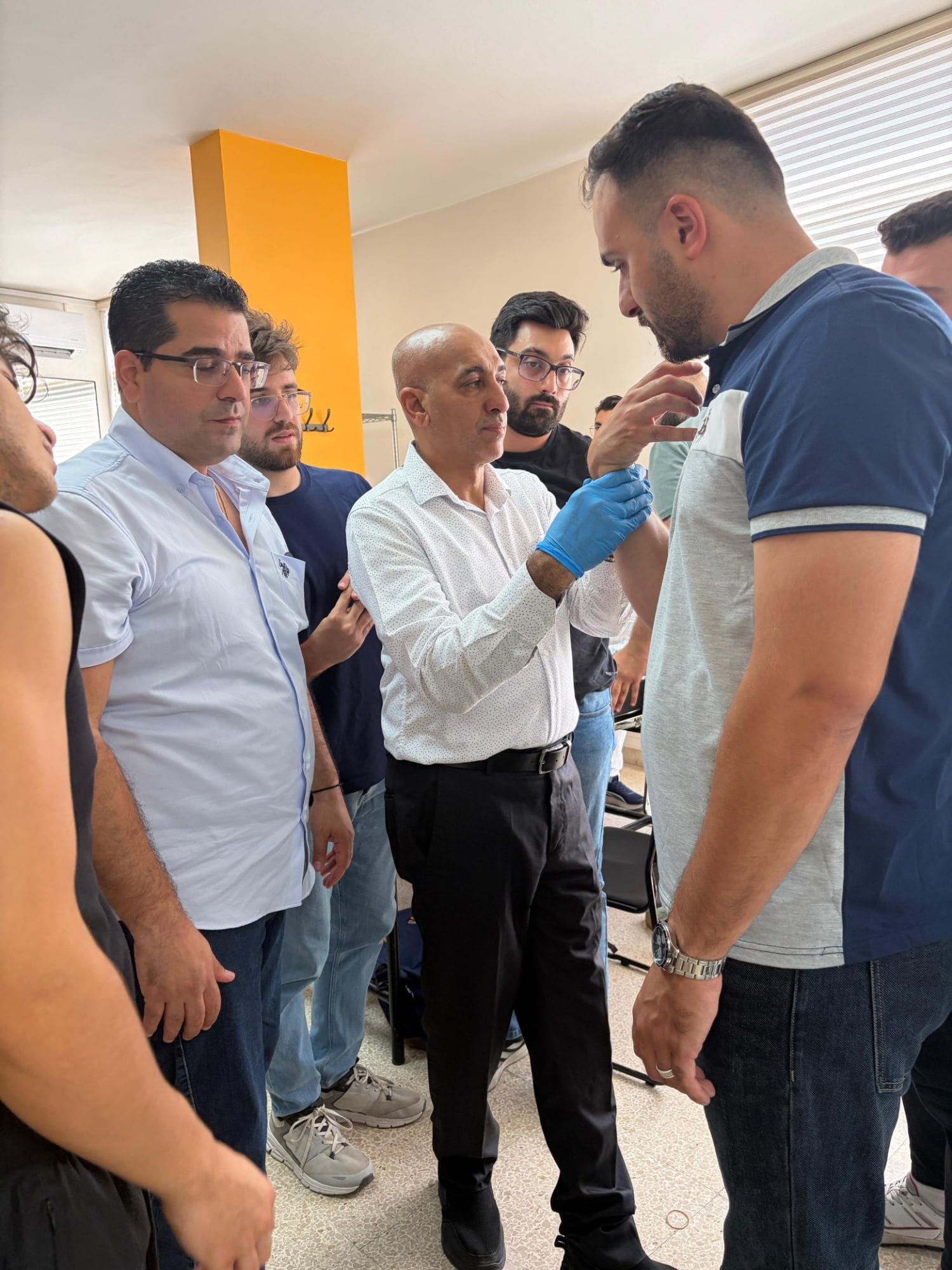 Dr. Hussein Nasser demonstrates an elbow mobilization technique to a group of gathered workshop participants