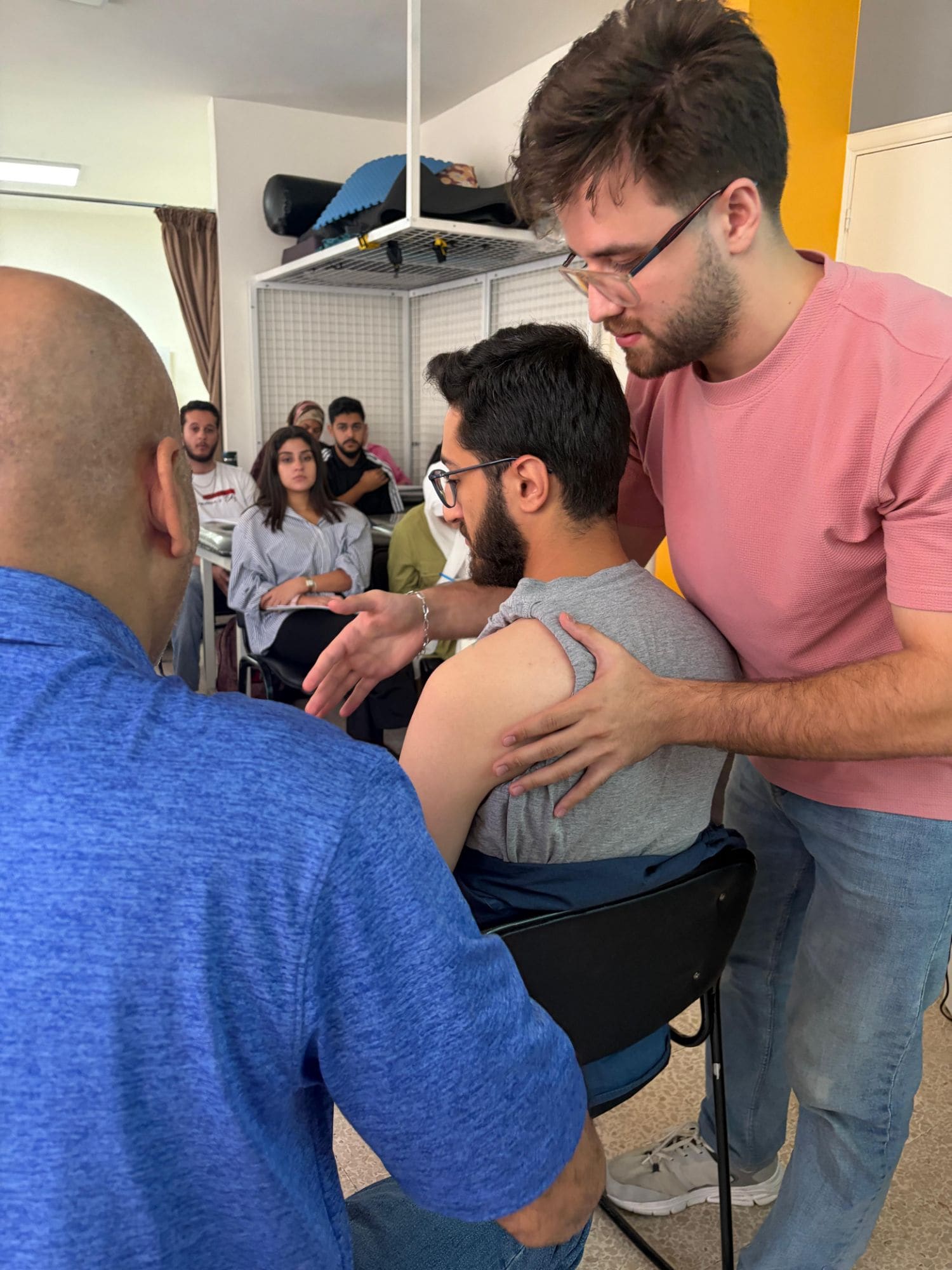 Two physical therapy students practice a shoulder mobilization technique on each other during the workshop