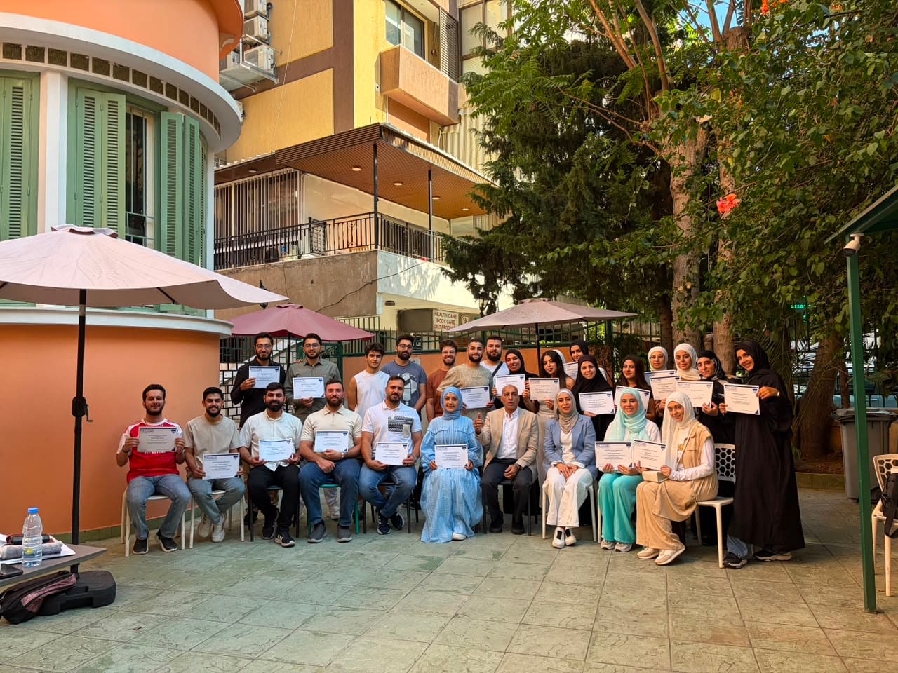 Workshop attendees hold their certificates of attendance in the courtyard at the close of the Mulligan workshop