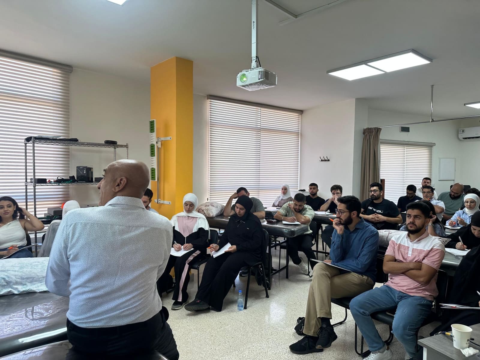Dr. Hussein Nasser addresses seated workshop participants taking notes in the classroom