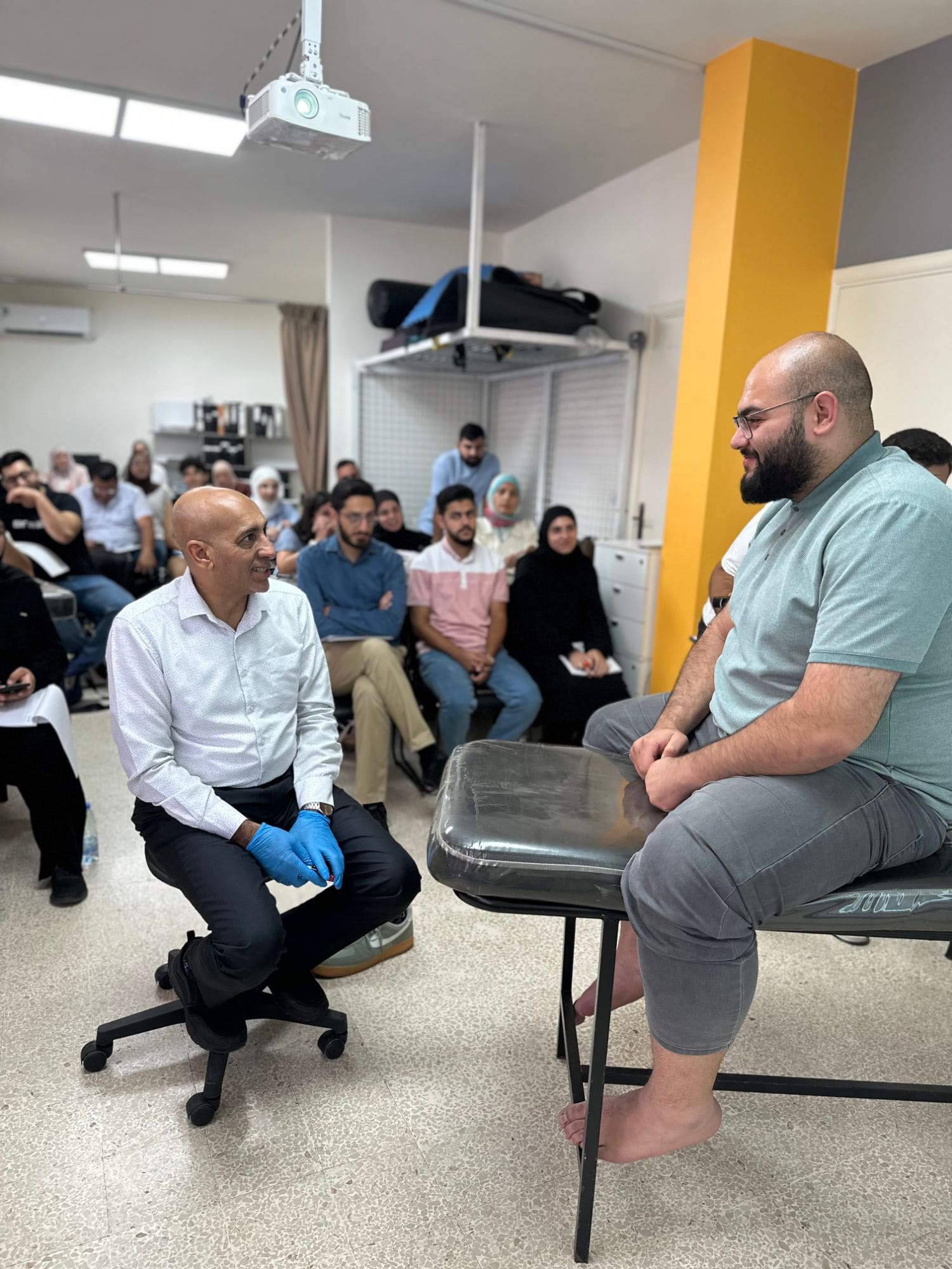 Dr. Hussein Nasser demonstrates an assessment technique with a seated participant on the treatment table