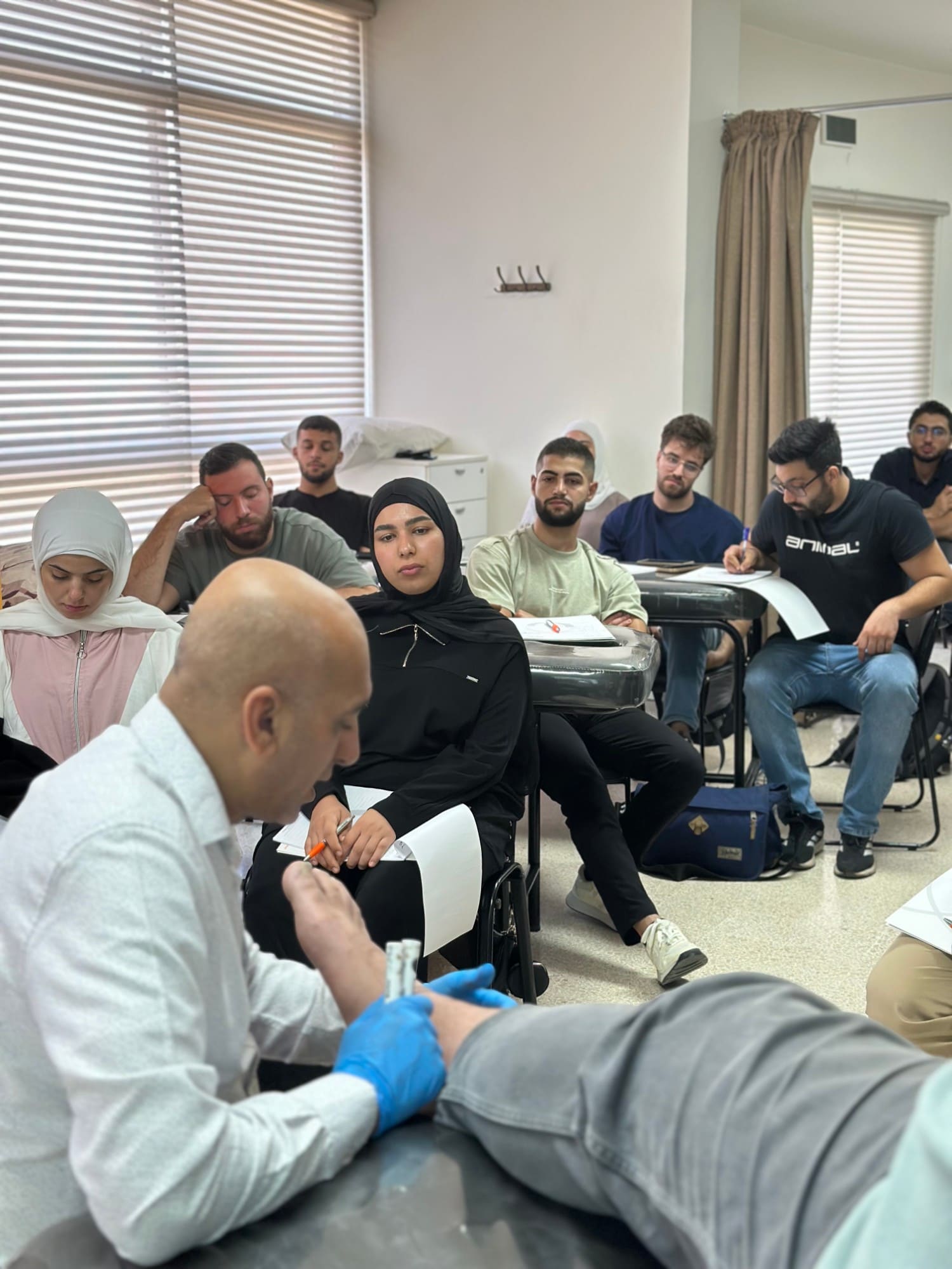 Dr. Hussein Nasser demonstrates a hand and wrist technique on a seated participant as others observe