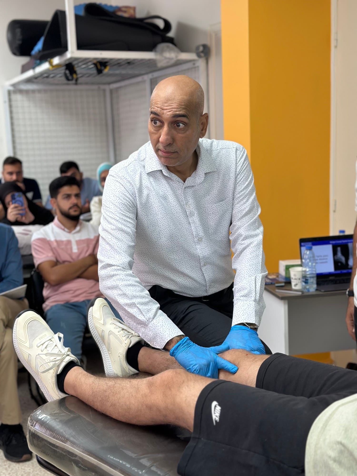Dr. Hussein Nasser performs a knee assessment technique on a participant on the treatment table